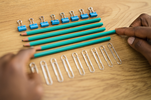 hands moving paper clips, pencils, and desk items into a uniform arrangement